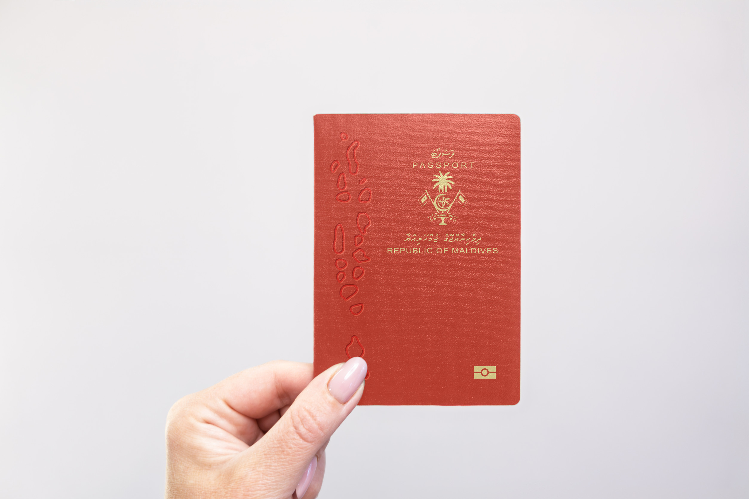 Maldives Passport Held In Hand Against A Plain White Background