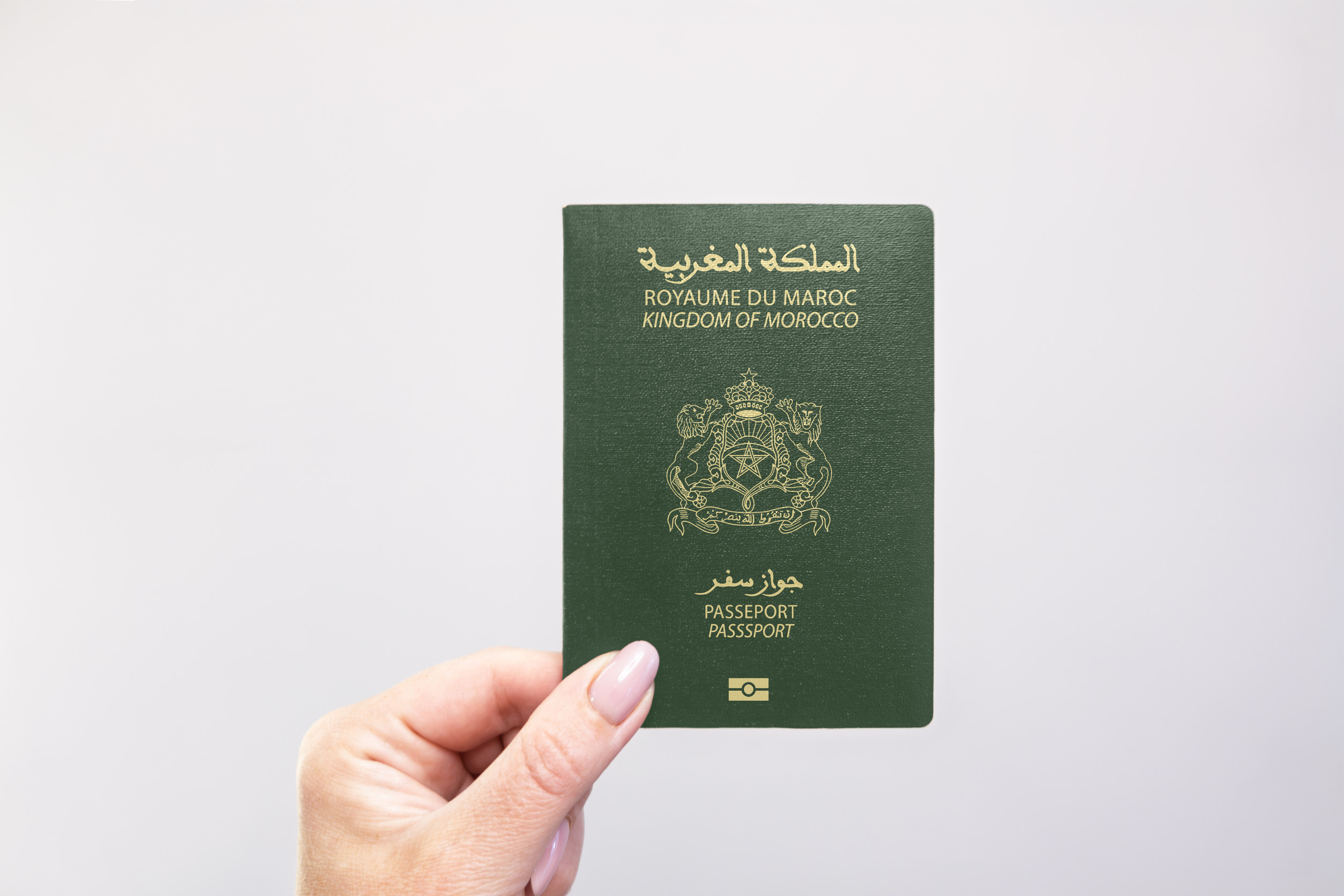 Morocco Passport Held In Hand Against A Plain White Background