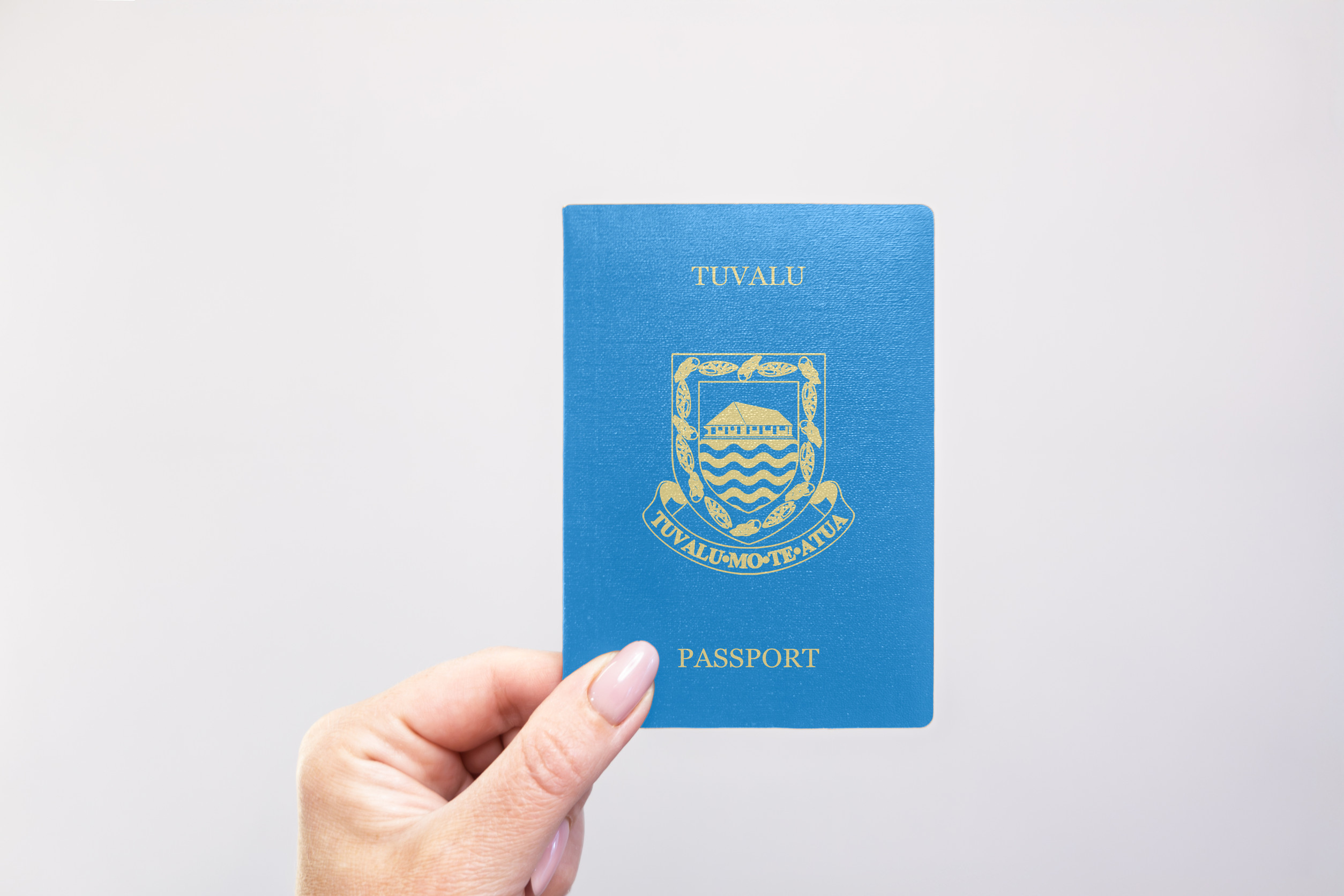 Tuvalu Passport Held In Hand Against A Plain White Background