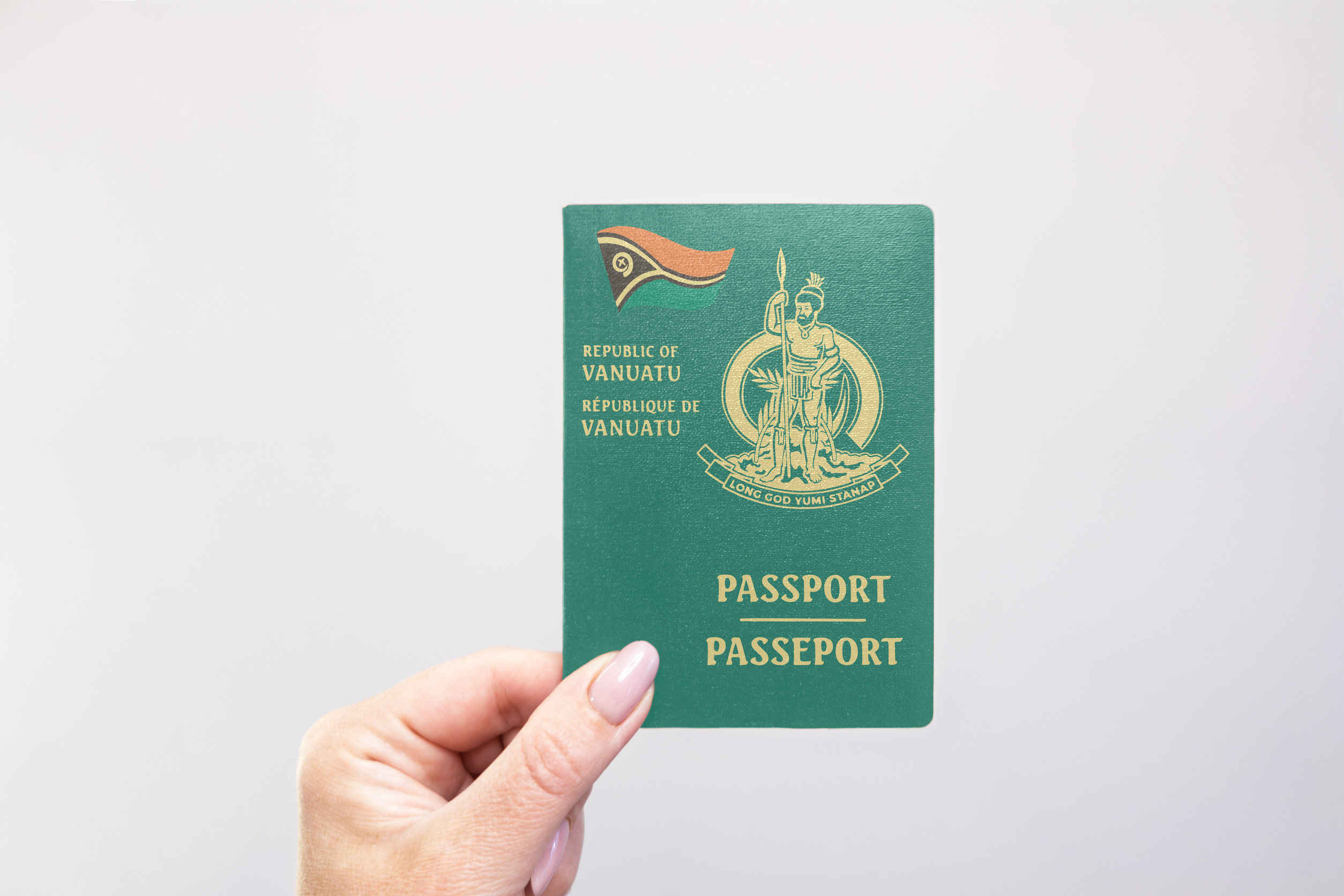 Vanuatu Passport Held In Hand Against A Plain White Background